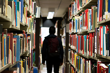 Student standing in between a book shelf